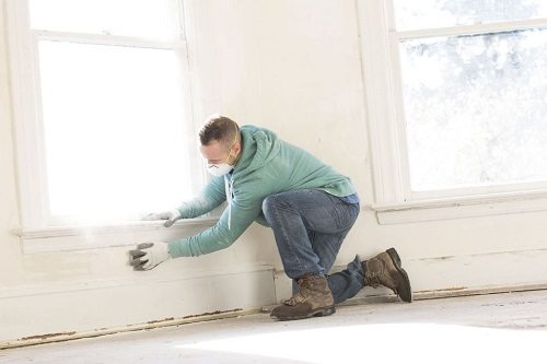 Man preparing the wall before painting it.
